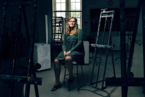 A student sits among easels and art supplies